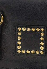 Borsa in pelle nera con una toppa quadrata decorata con borchie dorate disposte in un bordo. Include un anello metallico circolare per l'attacco.