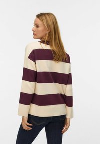 Gestreepte pullover trui in crème en donker pruim, gemaakt van een zachte stof. Heeft lange mouwen en een losse pasvorm met een ronde zoom.