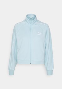 Veste zippée bleu clair en tissu texturé. Caractéristiques : rayures blanches le long des épaules et un petit logo blanc sur la poitrine.