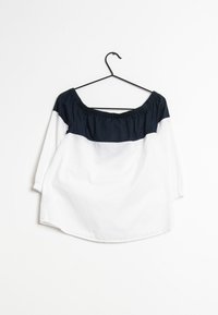 Weißes und marineblaues schulterfreies Shirt mit dreiviertel Ärmeln, einem gerafften Ausschnitt und lockerem Schnitt. Glatte Stofftextur.