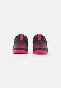 Baskets de sport noires avec des accents roses, dotées d'un upper en mesh, d'un col rembourré et d'un talon texturé pour une meilleure adhérence.