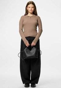 Top marrón de manga larga con textura de canalé y cuello, combinado con pantalones negros holgados y un bolso tejido negro texturizado con cierre de cordón.