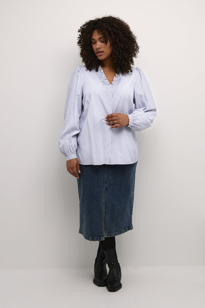 Striped long-sleeve blouse in light blue and white with a ruffled neckline; paired with a denim skirt and black ankle boots.