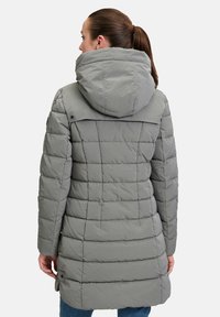 Grå polstret frakke med en aftagelig hætte, der har en quiltet tekstur og sideslidser ved kanten. Enkel, praktisk design.