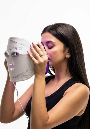 Biała maska LED do twarzy z purpurowymi akcentami, z wycięciami na oczy i wzorzystą powierzchnią. Kabel łączy się z ręką noszącego.