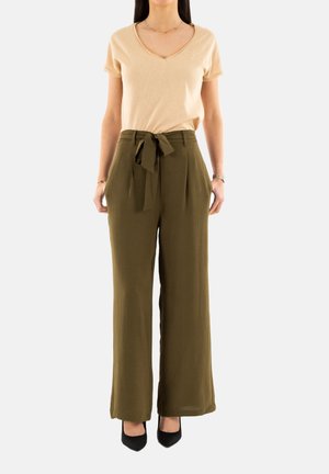 T-shirt beige a scollo a V abbinato a pantaloni verde oliva a vita alta con cintura annodata. I pantaloni sono a gamba larga con un tessuto strutturato.