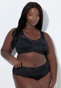 Completo intimo nero con reggiseno con inserti in rete e dettagli floreali, abbinato a slip a vita alta. Tessuto morbido e liscio.