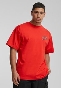 Rød bomulds T-shirt med korte ærmer, rund hals, med grafisk tekst "ALIVE!" på venstre brystområde, glat tekstur.
