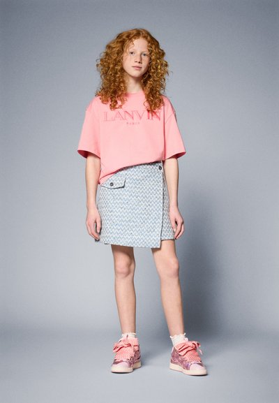 Camiseta de algodón rosa con el logo "LANVIN PARIS", falda corta azul con estampado y bolsillo lateral, y zapatillas rosas con lazos y detalles decorativos.