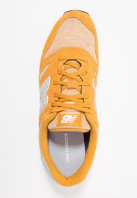 Baskets en daim orange et textile avec des accents gris, bout rond, fermeture à lacets, et logo sur la languette et le côté. Doublure intérieure douce.