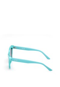 Ochelari de soare turquoise cu un cadru dreptunghiular plat, din material plastic neted și brațe subțiri. Prezintă marca "Guess" pe lateral.