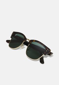 Ochelari de soare din scoică cu lentile de un verde închis, accente din metal auriu și rame groase. Prezintă tampoane nasale distinctive și detalii pe timpane.