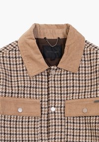 Bruine houndstooth jasje met beige corduroy kraag en knoopzakken. Bevat zilveren knopen en een "Gianni Lupo" label aan de binnenkant.