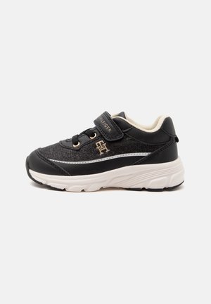 Sort og mørkegrå børnesneaker med hvid sål, velcrorem, dekorative snørebånd og lille mærkelogo på siden.