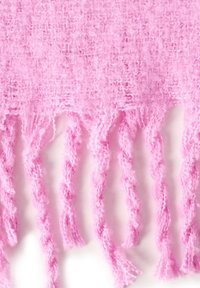 Zacht, pluizig roze gebreid stof met losjes gedraaide franjes die aan de rand hangen tegen een witte achtergrond.