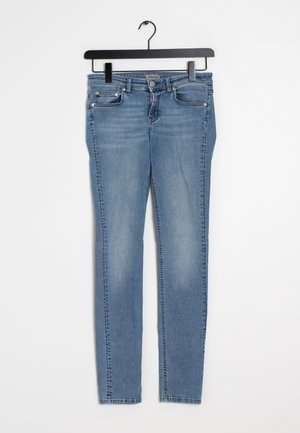 Hellblaue Slim-Fit-Jeans mit Fronttaschen und Gürtelschlaufen, an einem schwarzen Bügel vor weißem Hintergrund hängend.