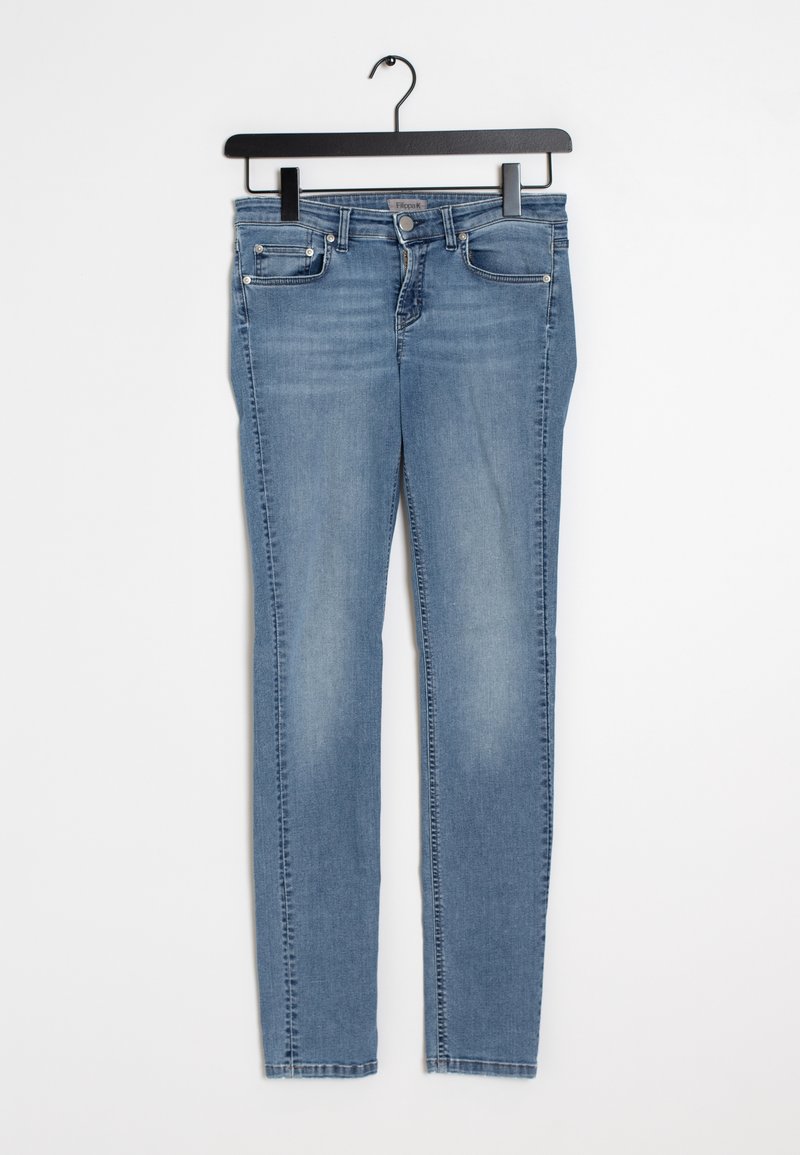 Jean slim bleu clair avec poches avant et passants pour ceinture, suspendu sur un cintre noir sur un fond blanc.