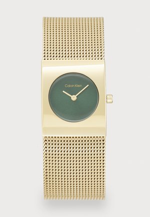 Montre en métal doré de forme rectangulaire avec un bracelet en maille. Cadran rond vert foncé, marqueurs d'heure dorés et aiguilles. Logo "Calvin Klein" à la position 12 heures.