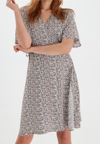Vestido envolvente floral en tela ligera que presenta mangas cortas, un escote en forma de V y un patrón colorido con flores en tonos rosa, azul y blanco.