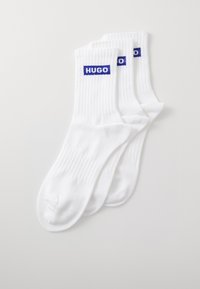 Weiße gerippte Socken mit blauem "HUGO"-Logo am Bündchen. Weiches Material, Standard Crew-Länge und nahtloses Zehendesign. Set mit drei Paaren.