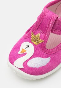 Pink fabric shoe featuring a white embroidered swan with a golden crown. Soft sole and elastic strap for easy wear. Smooth texture, casual design.