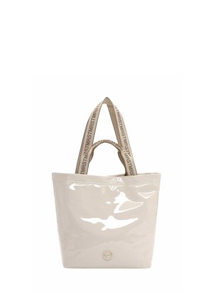 Sac fourre-tout beige brillant avec deux poignées en tissu imprimées d’un texte répétitif, et un petit logo métallique circulaire en bas au centre à l’avant.