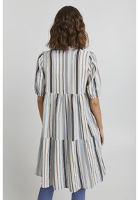 Abito a righe in tessuto leggero con design a strati. Presenta linee verticali blu, gialle e bianche. Le maniche a sbuffo aggiungono volume alle spalle.