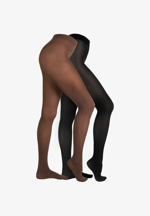 Frau trägt schwarzen BH, transparente schwarze Strumpfhosen und schwarze High Heels, steht in einer Gehpose vor weißem Hintergrund.