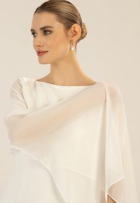 Flowing white dress made of lightweight fabric with sheer sleeves draping elegantly. Features a boat neckline and subtle texture.
