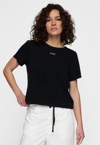 Zwart T-shirt met korte mouwen en ronde hals, voorzien van een klein logo-opdruk op de voorkant en een losse, ontspannen pasvorm.