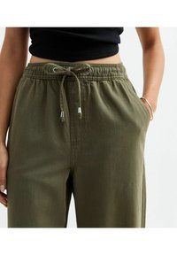 Pantalons vert olive en tissu léger, dotés d'une taille élastique avec cordon de serrage, de poches avant et d'une coupe décontractée.