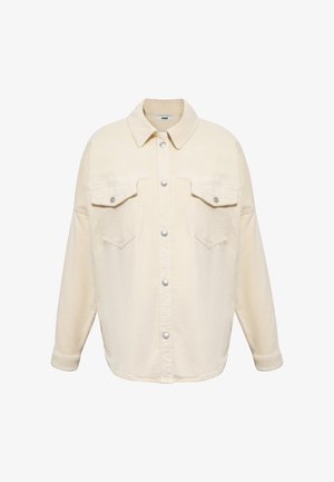 Cream corduroy shirt jacket with a pointed collar, two chest pockets, snap button closure, and relaxed fit. Textured fabric with vertical ridges.