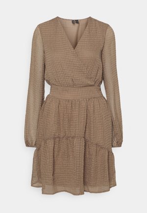 Robe marron clair texturée à manches longues, col en V, taille élastique et jupe à volants sur fond blanc uni.