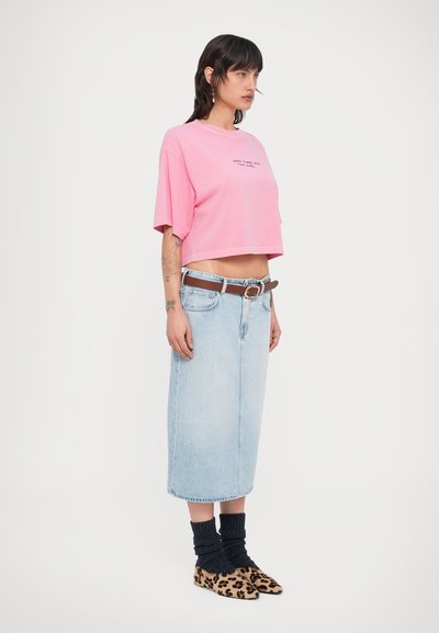 Ροζ κοντομάνικη μπλούζα με κείμενο, φούστα από ανοιχτό μπλε τζιν, καφέ ζώνη, μπλε καλτσάκια πλεκτά και μπεζ μπαλαρίνες με λεοπάρ σχέδιο.