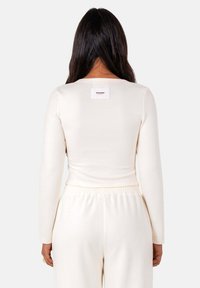 Langarmtop in off-white stof, met een vierkante halslijn, getailleerd ontwerp en een merkje op de achterkant.