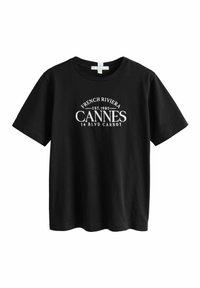 Musta puuvillapaita lyhyillä hihoilla, jossa on valkoista tekstiä: "FRENCH RIVIERA EST.1982 CANNES 14 BLVD CARNOT" edessä.
