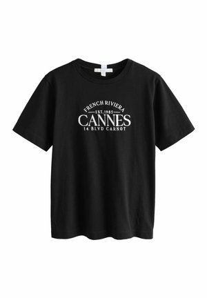 Černé bavlněné tričko s krátkými rukávy, na přední straně s bílým textem: "FRENCH RIVIERA EST.1982 CANNES 14 BLVD CARNOT".