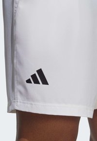 Hvide atletiske shorts lavet af glat stof, med et sort Adidas-logo og tre diagonale striber nær kanten.