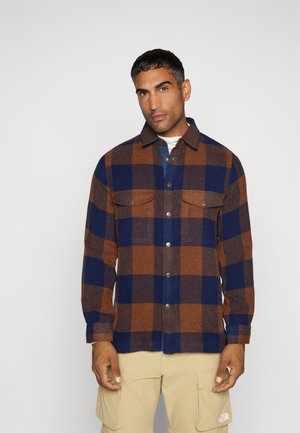 Flanellen shirt met een blauw en bruin ruitpatroon, knoopsluiting aan de voorkant, twee borstzakken en een klassieke kraag.