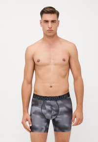Herren Boxerbriefs in einem dunkelgrauen Camouflage-Muster, aus glattem Material hergestellt. Mit einem breiten schwarzen Bund, der mit "ARMOUR"-Branding versehen ist.