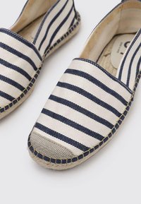 Espadrilles de lona a rayas en color crema y azul marino, con una suave suela de goma, bordes cosidos y punta redondeada.