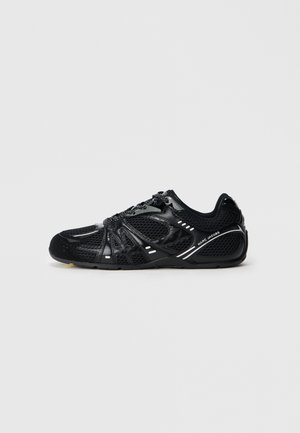 Black mesh and leather low-top sneaker with reflective accents and "Marc Jacobs" branding on side, flat sole, and lace-up closure.