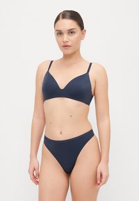 Granatowy bikini składający się z bezszwowego biustonosza z głębokim dekoltem w serek i regulowanymi ramiączkami, połączony z wysokoskalnymi majtkami dla uzyskania smukłej sylwetki.