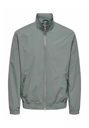 Grå lett jakke med hel frontglidelås, elastiske mansjetter og kant, samt glidelåslommer i sidene, vist på hvit bakgrunn.