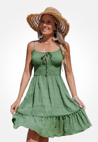 Vestito verde con tessuto strutturato, spalline sottili regolabili, chiusura anteriore con laccio e gonna arricciata con orlo a volant.