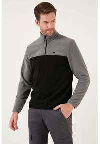 Fleece pullover i grå og sort med halv lynlås, ståkrave og et lille logo. Tekstureret stof med lange ærmer og afslappet pasform.
