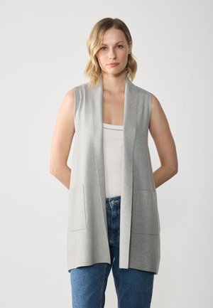 Light gray sleeveless cardigan with a deep V-neck, open front, and front pockets, made of soft knit fabric. Model wearing blue jeans.