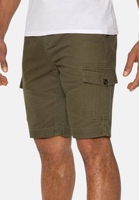 Pantalones cortos cargo de color verde oliva, fabricados en algodón, que cuentan con múltiples bolsillos, cierre de botón y detalles de costura visibles.