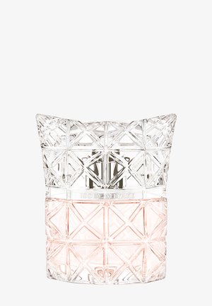 Flacon de parfum en verre taillé au diamant avec liquide rose clair, motif géométrique, et "ISSEY MIYAKE" gravé sur le col.