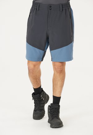 Grå og blå shorts med elastisk talje, sidelommer og kontrasterende paneler; parret med sorte vandrestøvler og sorte sokker.